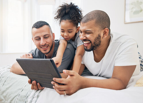 Gay family, tablet and child on a bed at home for e learning, watch video and education on internet. Adoption, lgbt men or parents with a happy kid and technology for streaming movies, games or app