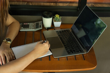 The dedicated businesswoman sits poised at her desk, diligently recording every expense in a...
