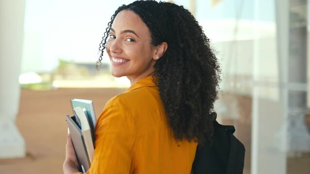 Happy woman. Close-up of a happy lovely brazilian or hispanic female student, with a backpack and notebooks in her hand, walks near the university campus, turns and smiles at the camera