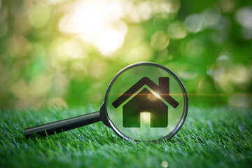 Hand holding a magnifying glass with natural house icon on green grass background to search eco-friendly, energy-saving home selection concept.Hunting.Inspection real estate rent, purchase and sale. - obrazy, fototapety, plakaty
