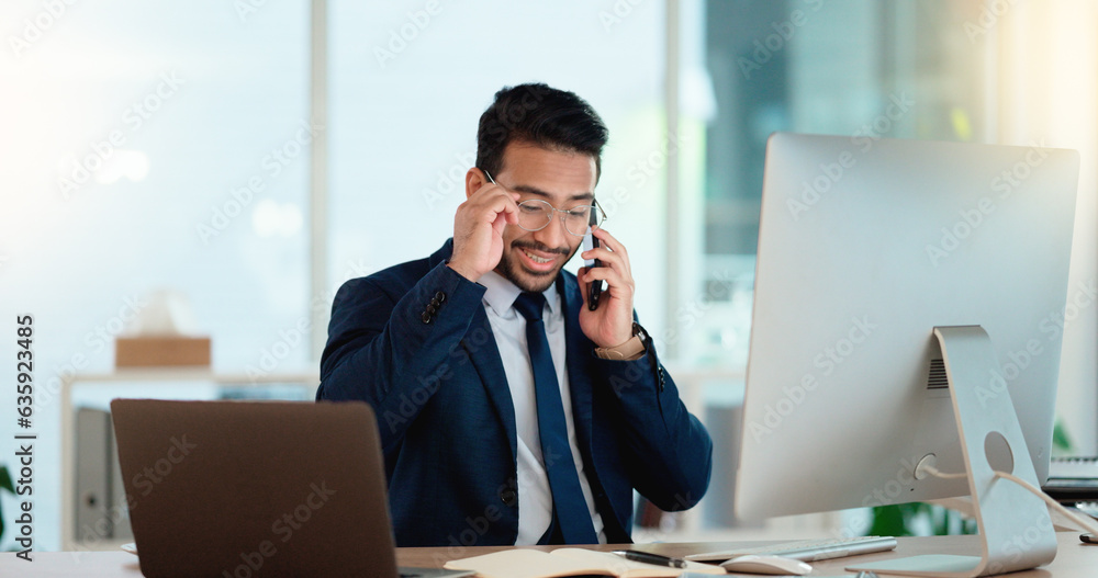 Aufkleber Happy business man talking on his phone while working on a computer and smiling alone at work. Young corporate professional having a discussion and explaining project details to a colleague or client