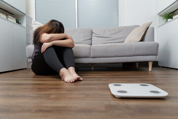 Sad woman with fat upset bored of dieting Weight loss fail  Fat diet and scale sad asian woman on weight scale at home weight control