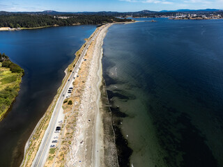 Aerial sand spit with a long straight road with people on vacation and cars parked in Victoria British Columbia Canada..