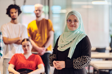 A diverse group of young business people congregates within a modern startup's glass-enclosed office, featuring inclusivity with a person in a wheelchair, an African American young man , and a hijab