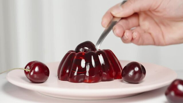 I use a spoon to scoop out a piece of red jelly with a cherry on top.