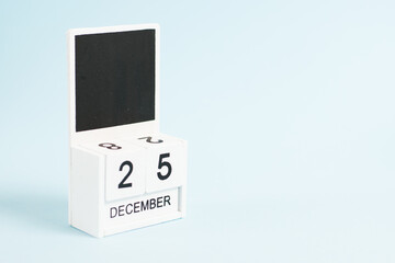 Christmas, wooden calendar with the date December 25 on a blue background with copy space. The concept of preparing for the celebration of Christmas and New Year and plans for the future.