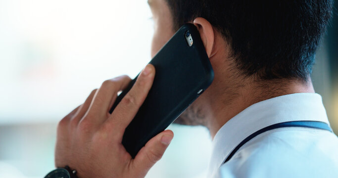 Business man talking on a phone call in an office. Closeup of corporate professional and entrepreneur from the back networking to build a successful empire. Communicating plans and deals with clients