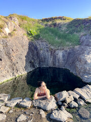 The young woman was happily soaking in the hot spring. The water in the pond comes from geothermal heat in Iceland, in an open-air bath overlooking the natural surroundings.