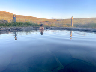 The young woman was happily soaking in the hot spring. The water in the pond comes from geothermal heat in Iceland, in an open-air bath overlooking the natural surroundings.