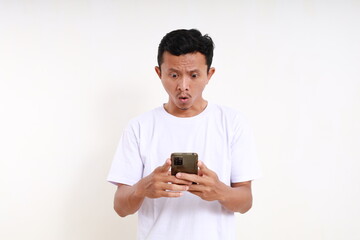 Shocked asian funny man standing while holding a cell phone. Isolated on white background