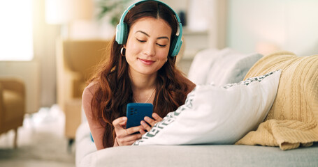 Relax, music and phone with woman in living room and headphones listening to radio, podcast or podcast. Happy, freedom and internet with girl on sofa, streaming for audio, social media or online