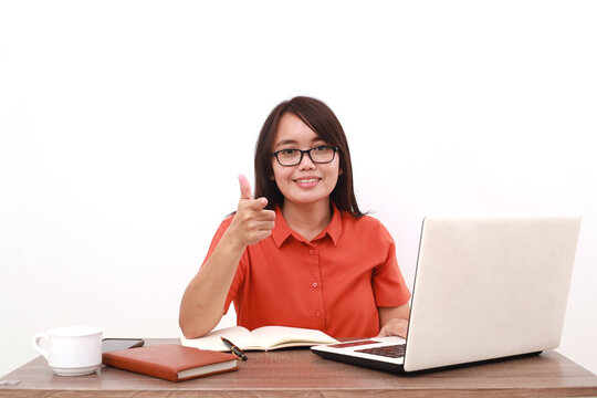 Optimistic young asian entrepreneur woman sitting with laptop on the desk while pointing on you