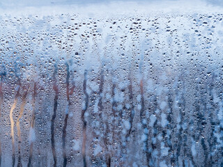 Window glass close-up, showing severe water droplet condensation. Trapped moisture in between double glazing. Concept cold weather, high humidity, temperature change, ventilation and house defect.
