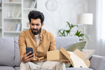 Upset and annoyed man received a parcel, Latin American dissatisfied with the delivery service sits...