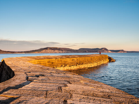 People at the end of The Cobb enjoying the evening light, Lyme Regis, Dorset, England, United Kingdom