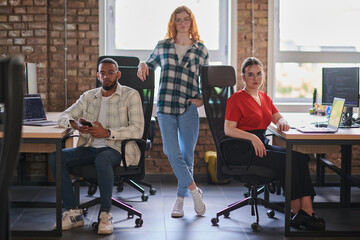 A diverse group of young business individuals congregates in a modern startup coworking center,...