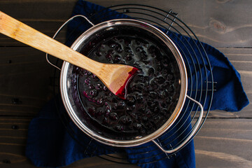 Homemade Blueberry Compote in a Small Pot with a Wooden Spoon: Blueberry compote with a wooden spoon in a saucepan - obrazy, fototapety, plakaty