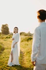 loving couple of newlyweds in a field in nature in summer. Romantic walk of lovers at sunset.
