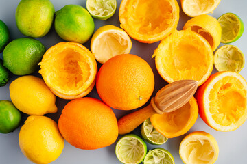 Whole and Juiced Citrus Fruit with a Wooden Citrus Reamer: A manual juicer surrounded with whole and halved oranges, lemons, and limes