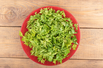 Top view of chopped parsley leaves in a plate over wooden background.