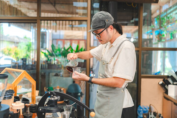 Barista at a coffee shop preparing filter coffee, Cheerful barista wearing apron while preparing coffee at an automatic machine in a modern beverage cafe, Professional hipster barista making drip brew