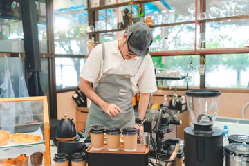 Fototapeta na wymiar Barista at a coffee shop preparing filter coffee, Cheerful barista wearing apron while preparing coffee at an automatic machine in a modern beverage cafe, Professional hipster barista making drip brew