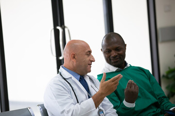 Mature female doctor discussing medical report with nurses in hospital hallway. Senior general practitioner discussing patient case status with group of medical staff after surgery. Doctors working.