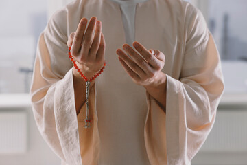 Obraz premium Muslim man with misbaha praying near window indoors, closeup