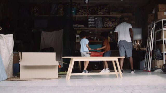 Young mixed race family cleaning up the garage and packing away tools