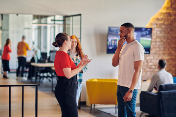 Young business colleagues, including an African American businessman, engage in a conversation about business issues in the hallway of a modern startup coworking center, exemplifying dynamic problem