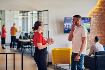 Young business colleagues, including an African American businessman, engage in a conversation about business issues in the hallway of a modern startup coworking center, exemplifying dynamic problem