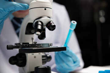 male medical scientist examining specimen using microscope in modern laboratory.