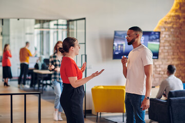 Young business colleagues, including an African American businessman, engage in a conversation about business issues in the hallway of a modern startup coworking center, exemplifying dynamic problem