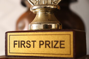 Closeup of a gold Trophy with written print of First Prize with selective focus 