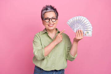 Portrait of successful wealthy positive lady toothy smile direct finger arm hold dollar bills...