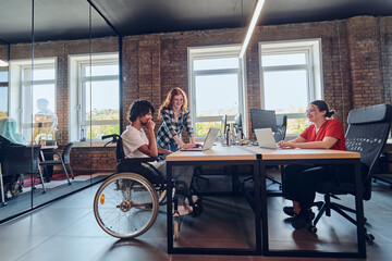 A young business group, including an African American businessman in a wheelchair, collaborates...