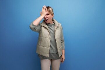 blonde 30s woman upset because of stupidity on studio blue background