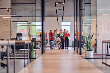 Fototapeta premium A diverse group of young business people congregates within a modern startup's glass-enclosed office, featuring inclusivity with a person in a wheelchair, an African American young man , and a hijab