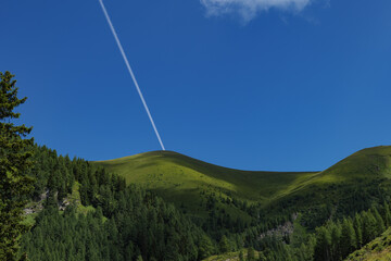 Contrail of a flying plane over the mountains on a sunny day
