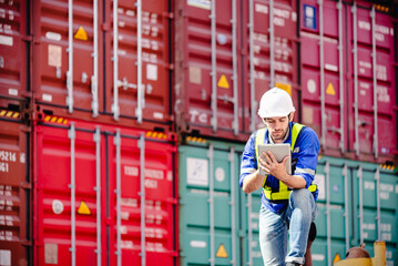 Engineer or Technician wears hardhat and reflection cloth looking at tablet for check his job order with cargo stacked container in background. Engineering site and working with technology concept.