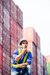 Portrait of Engineers or industrial workers using walkie-talkie command, communicate to shipping cargo freights colleague with background of cargo containers at shipping container yards and port yards