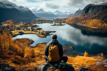 A man with a tourist backpack in the mountains looks at the valley from the top of the mountain. Hiking in picturesque places.