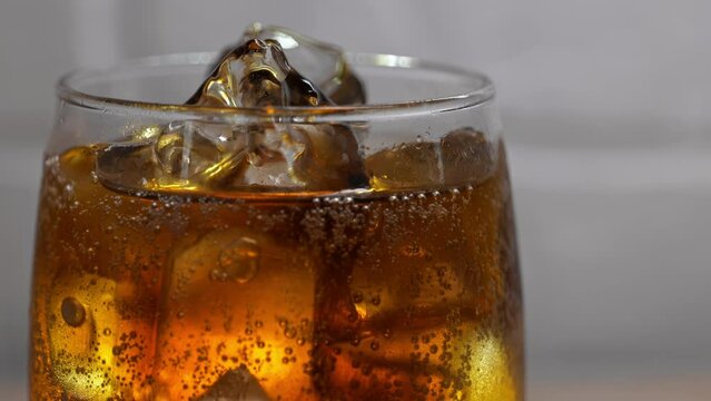 cold drink close up video: add some cola to the glass with ice
