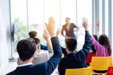 Business person raising hand during seminar. Hand up in conference asking to answer a question in business meeting room and seminar class. - obrazy, fototapety, plakaty