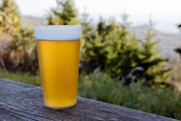 Glass of beer captured in the foreground of a tranquil mountain view