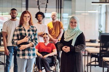 A diverse group of young business people congregates within a modern startup's glass-enclosed office, featuring inclusivity with a person in a wheelchair, an African American young man , and a hijab