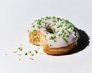 Close up of a half-eaten glazed doughnut with green sprinkles