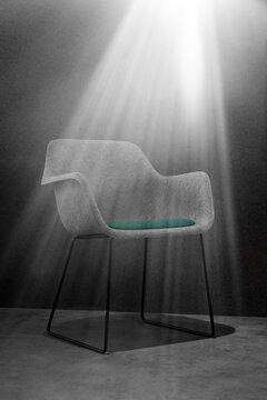 Grey felt chair with green pillow in the spotlight