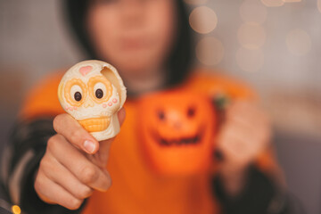 Portrait of candid authentic zoomer boy posing with jack lantern mug and sweets at halloween party