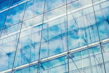 View upwards Double-skin glass facade of a modern office building reflecting the clouds in the sky